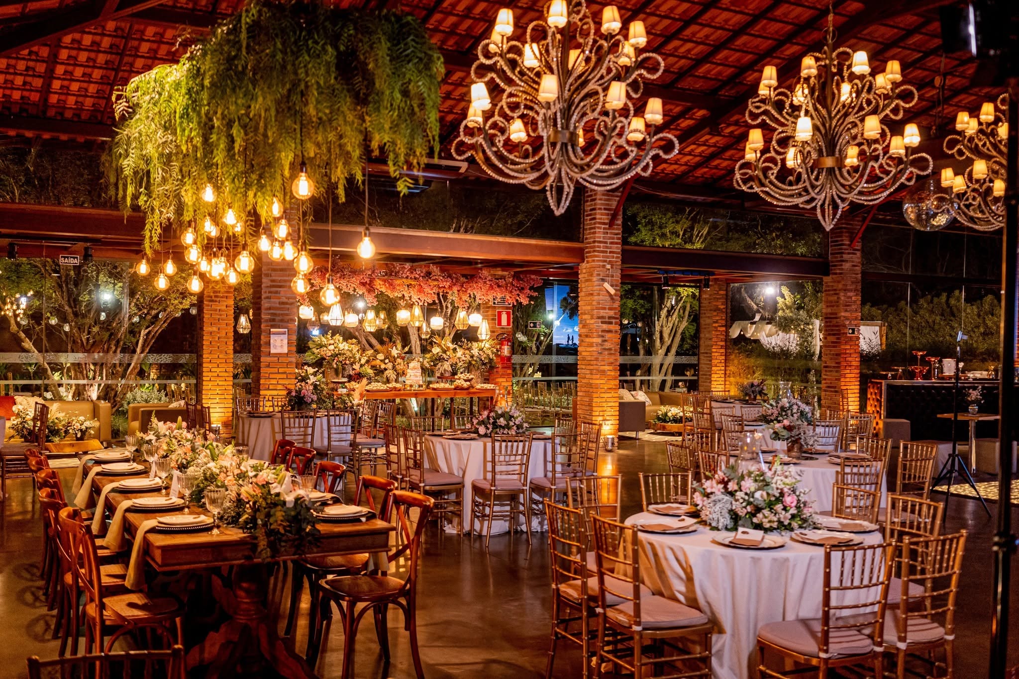 O salão de festas do Lanai iluminado pelos chandeliers de madeira e velas, com mesas postas para os convidados.