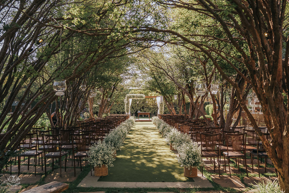 A Alameda de Jabuticabeiras do Lanai: um corredor de árvores enquadrando o altar, com cadeiras de madeira e arranjos brancos.